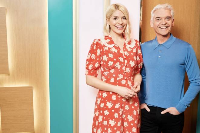Holly Willoughby and Phillip Schofield stand against a multi-coloured wall in the This Morning studio.